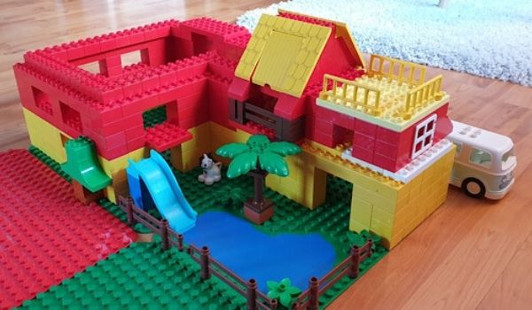 Ein Haus gebaut aus Lego, mit einem Spielplatz und einem VW-Bus.