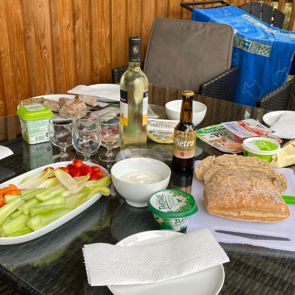 Ein gedeckter Tisch mit Gemüsestäbchen, Brot, Fleisch und Muskat-Wein. 